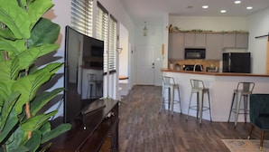 Une cuisine moderne avec un coin bar, un plancher en bois et des tabourets de bar.