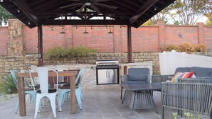 Une terrasse extérieure avec un mur en briques, un barbecue et un espace salon.
