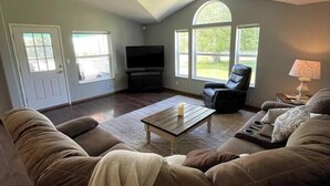 A living room with a high ceiling, a flat-screen TV, a sofa, a coffee table, and a chair. - Rosie's Surf Shack: 3 BR, 2 BA house in beautiful Grays Harbor (Grays Harbor County)