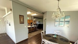 A spacious dining area with a chandelier, a round table, and white chairs. - Rosie's Surf Shack: 3 BR, 2 BA house in beautiful Grays Harbor (Grays Harbor County)