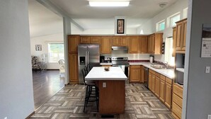 A modern kitchen with wooden cabinets, a central island, and a herringbone-patterned floor. - Rosie's Surf Shack: 3 BR, 2 BA house in beautiful Grays Harbor (Grays Harbor County)
