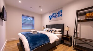 Relax in this cozy bedroom with a large bed, flat-screen TV, and natural light from the window.