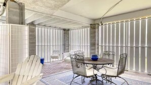 A covered patio area with a round table and chairs, a blue bowl, and a white chair. - Bay Breeze - 3 Min Walk to Beach (Tybee Island)