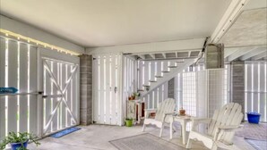 A spacious room with a large white door, a staircase, and two white chairs. - Bay Breeze - 3 Min Walk to Beach (Tybee Island)