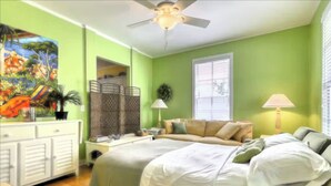A bedroom with a bed, bedside table, lamp, and a painting on the wall. - Bay Breeze - 3 Min Walk to Beach (Tybee Island)