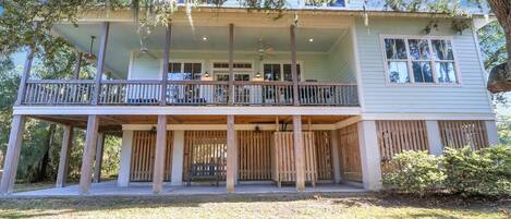 A two-story house with a balcony, a covered porch, and a wooden fence.