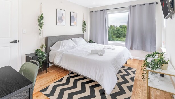 A modern bedroom with a bed, a desk, and a TV. - City Center Oasis Newark (Newark)
