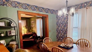 Ein Essbereich mit Holztisch und Stühlen, einem Bücherregal und einer Wand mit Blumenmuster.