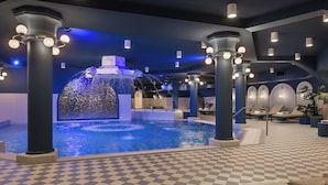 Un hall d’hôtel doté d’une piscine centrale, de coins salon et d’un élément décoratif aquatique.