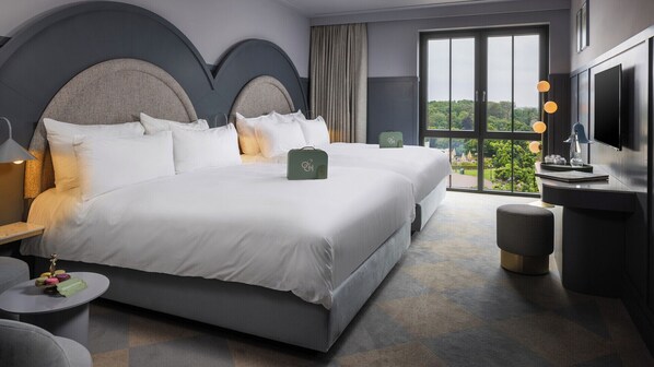 A hotel room with a large bed, a desk, a chair, a TV, and a view of greenery through the window. - Efteling Grand Hotel - Theme Park tickets included (Kaatsheuvel)