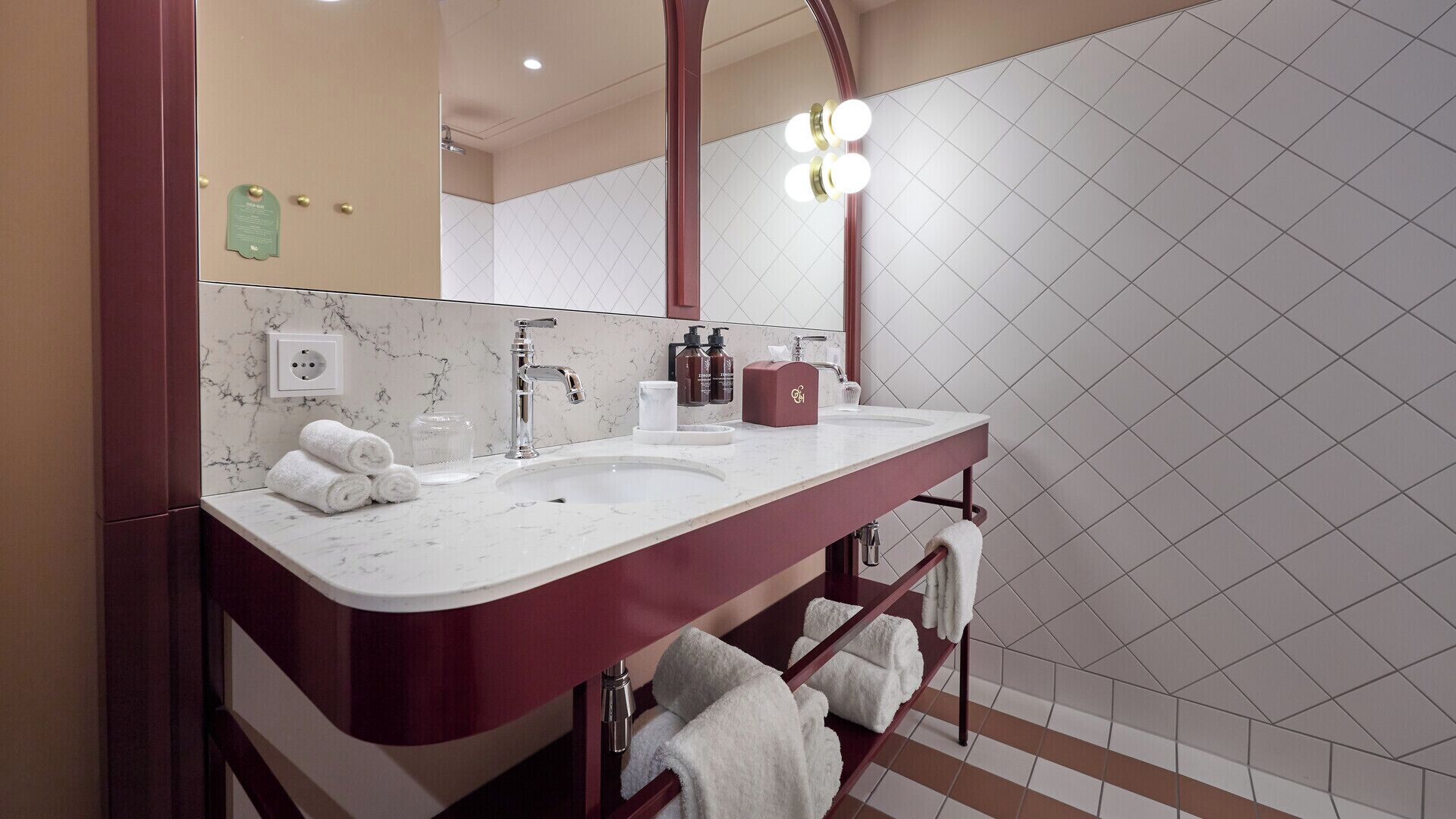 A bathroom with a marble vanity, a large mirror, and a shower area.