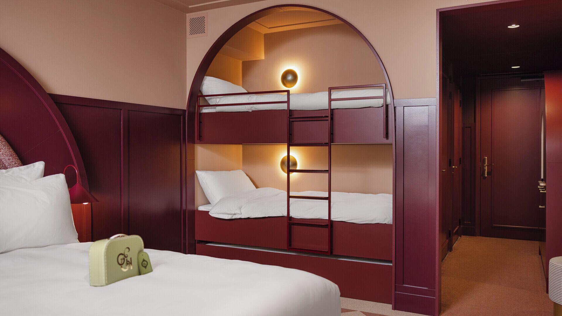 A hotel room with a bunk bed, a desk with a phone, and a wardrobe.