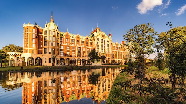 Un grand bâtiment somptueux, doté de nombreuses tours et de coupoles, qui se reflète sur une étendue d’eau calme.