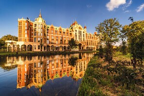 A large, ornate building with multiple towers and domes, reflecting on a calm body of water. - Efteling Grand Hotel - Theme Park tickets included (Kaatsheuvel)