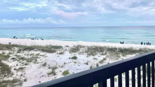 Una playa con vista al océano y una zona arenosa con vegetación escasa.