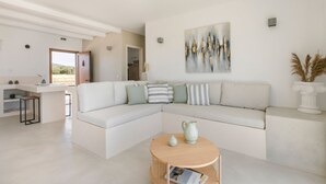 Un salon moderne avec un canapé blanc, une table basse ronde et un tableau accroché au mur.