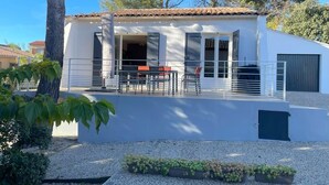 A modern house with a patio, outdoor seating, and a gravel driveway.