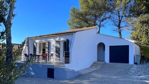 A modern house with a covered patio, a garage, and a gravel driveway.