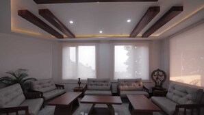 A modern living room with a sofa set, coffee tables, and a decorative statue. - Shivani Foods And Resort (Ranikhet)