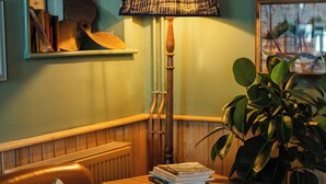 A cozy corner with a leather armchair, a table with books, a lamp, and a potted plant. - The Dolphin (Beer)