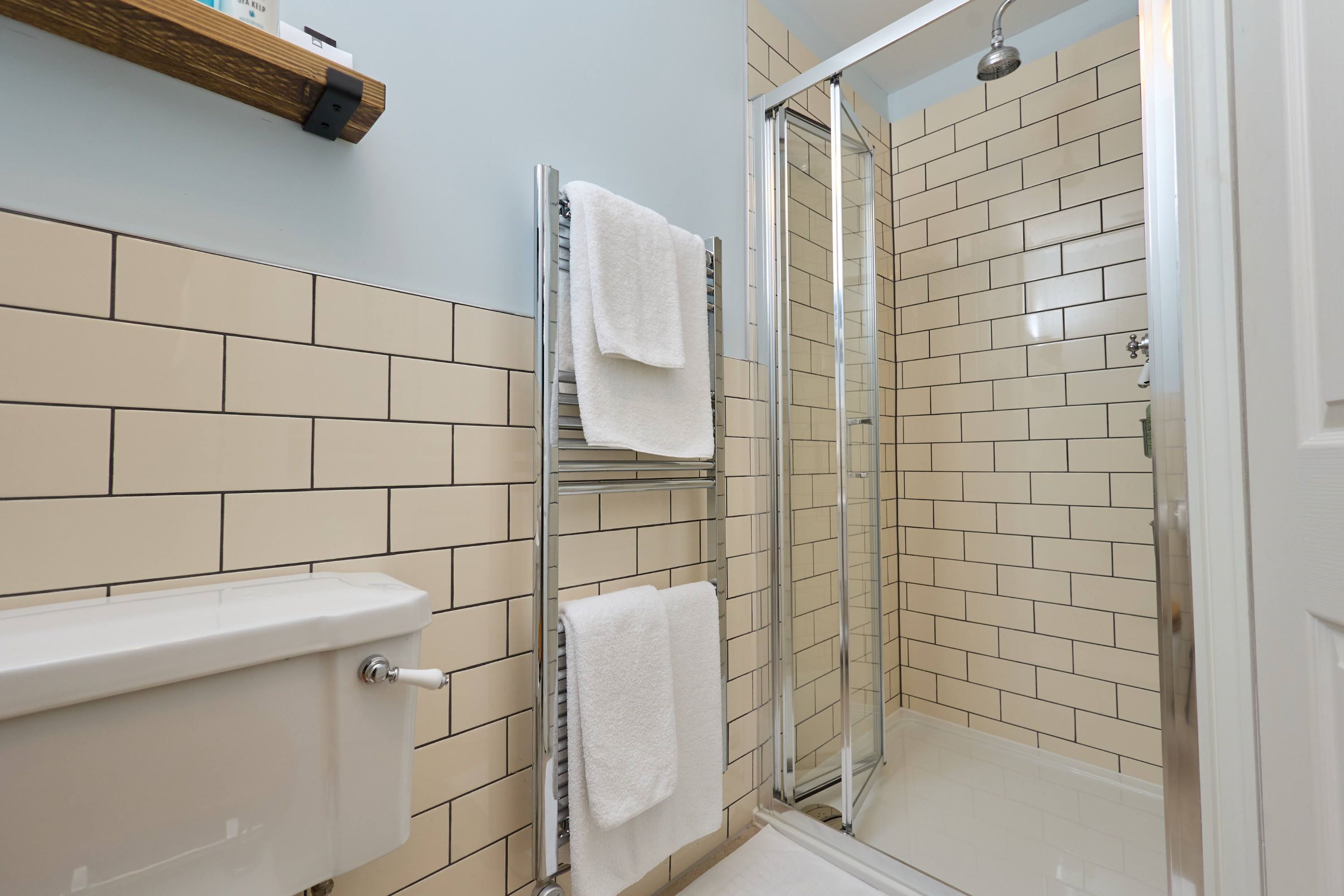 A bathroom with a toilet, a glass shower enclosure, and a towel rack.