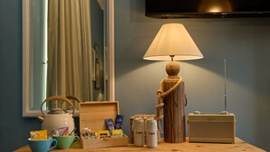 A wooden table with a lamp, a radio, and various items including a kettle, cups, and cans. - The Dolphin (Beer)