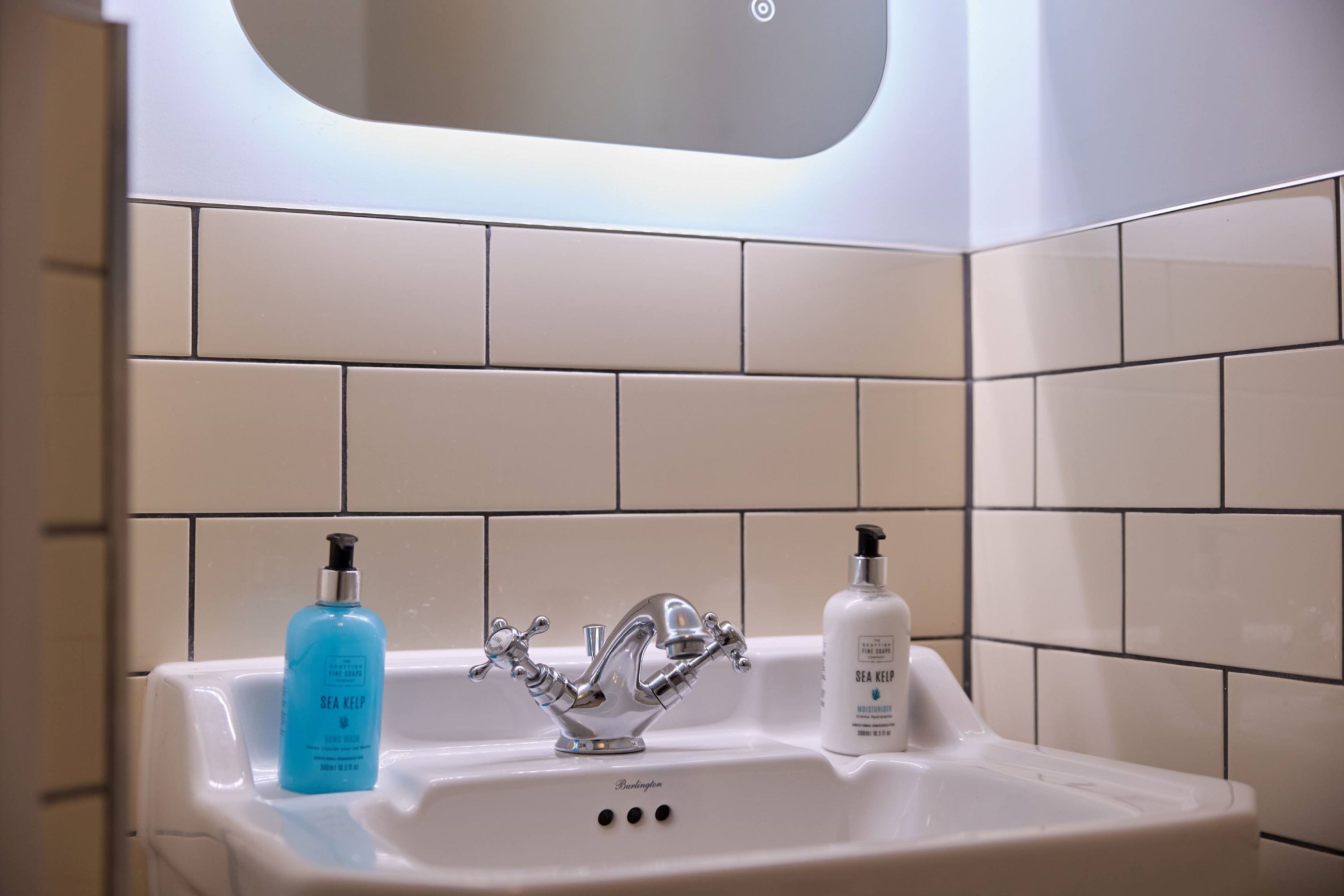 A bathroom sink with two bottles of hand soap and a modern faucet.