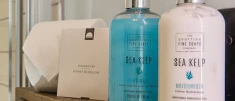 Un estante de madera con dos botellas de jabón de manos Sea Kelp y un gorro de ducha.