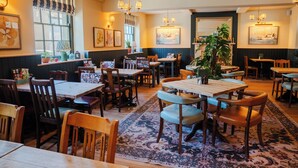 A restaurant with wooden tables and chairs, a large rug, and wall-mounted artwork. - The Dolphin (Beer)