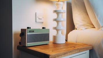 A wooden bedside table with a vintage radio and a modern lamp.
