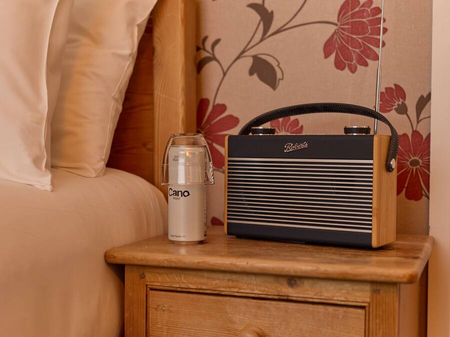 A bedside table with a radio and a glass of water.