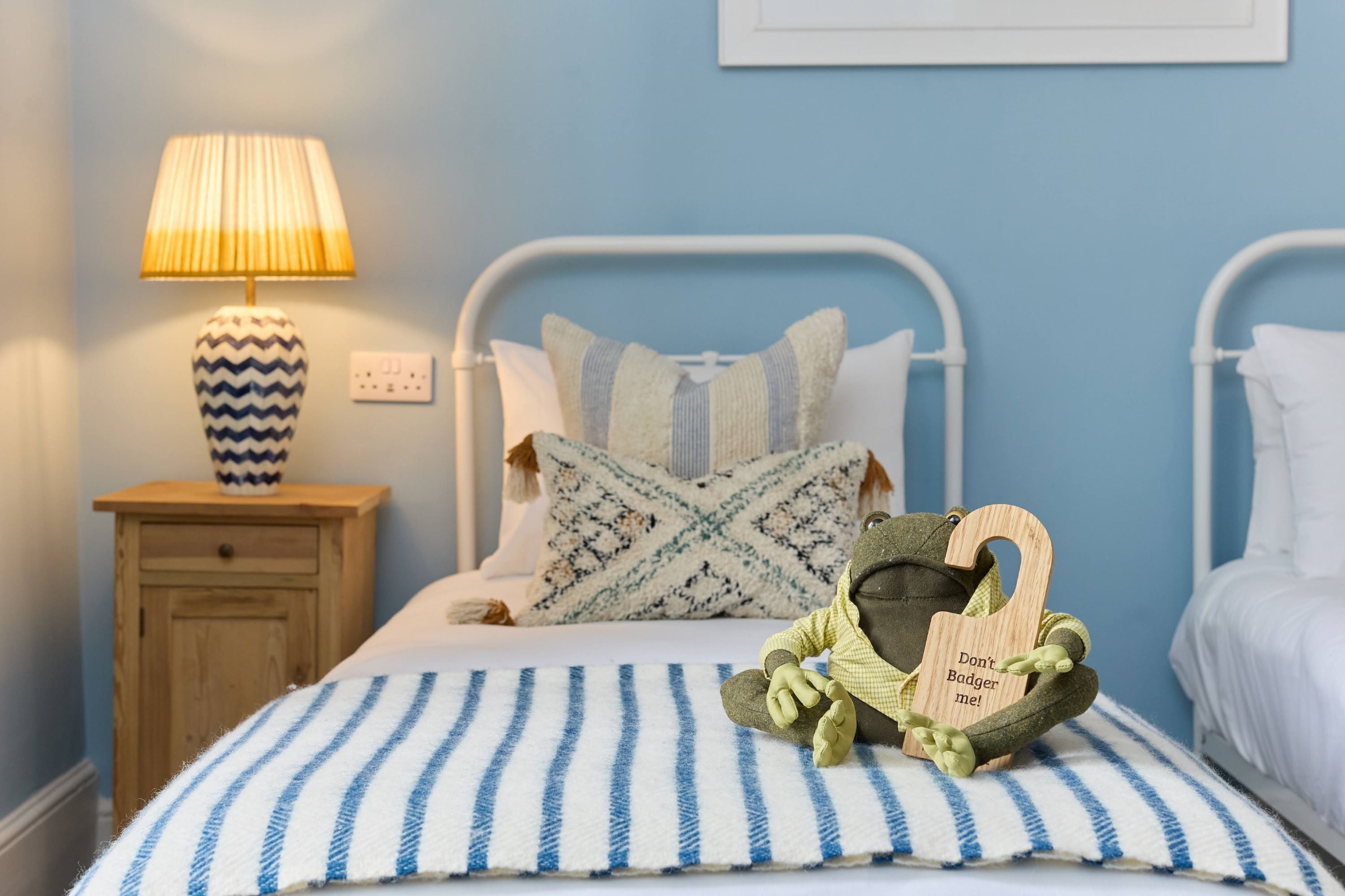 A bedroom with a bed, a nightstand, a lamp, and a plush toy.