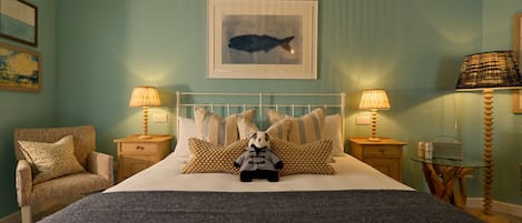 A neatly arranged bedroom with a bed, pillows, a chair, and a bedside table with lamps.