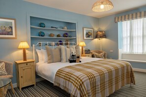 Ein ordentlich eingerichtetes Schlafzimmer mit Bett, Nachttischen, einem Regal mit Dekoration und einem Fenster mit Vorhängen.
