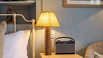 Una mesita de noche con una lámpara, una radio y una cama con almohadas.
