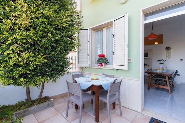 A dining area with a table set for four, surrounded by chairs, and a window with white shutters.