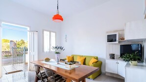 Een moderne keuken met een houten eettafel, een groene bank en een witte kast met een televisie.