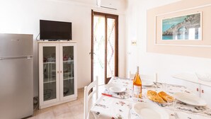 Un coin repas avec une table dressée pour deux personnes, un téléviseur placé au-dessus de la porte et un meuble avec des portes en verre.