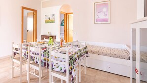 A dining area with a table set for two, a bench, and a white cabinet.