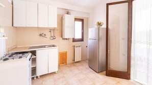 A compact kitchen with white cabinets, a stainless steel refrigerator, and a gas stove.