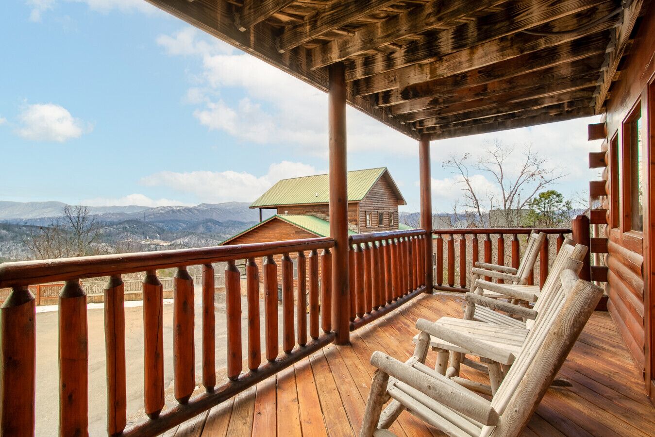 A wooden deck with a railing, wooden benches, and a view of a mountain landscape.