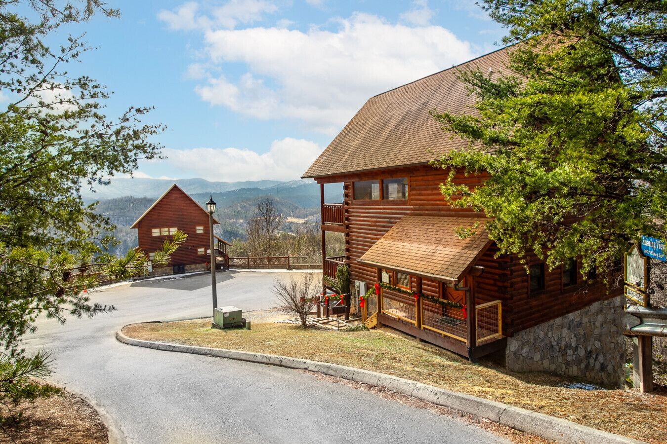 Une cabane en bois avec des fondations en pierre, une allée sinueuse et une vue sur les montagnes en arrière-plan.