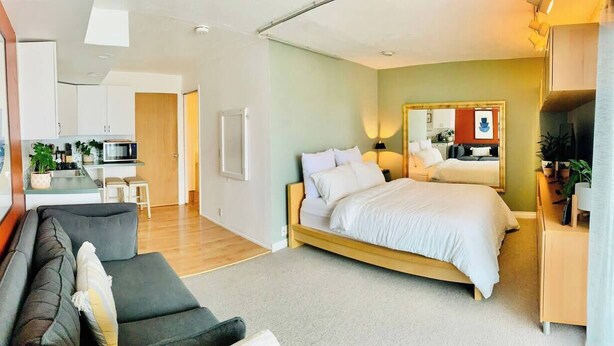 Una habitación de hotel moderna con cama, sofá, kitchenette y baño.