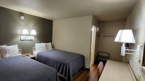 A hotel room with two single beds, a small desk, and a chair. There are wall-mounted lamps and a ceiling light. - AMERICAN INN (Temple)