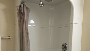 A corner bathroom with a shower, toilet, and sink. - AMERICAN INN (Temple)