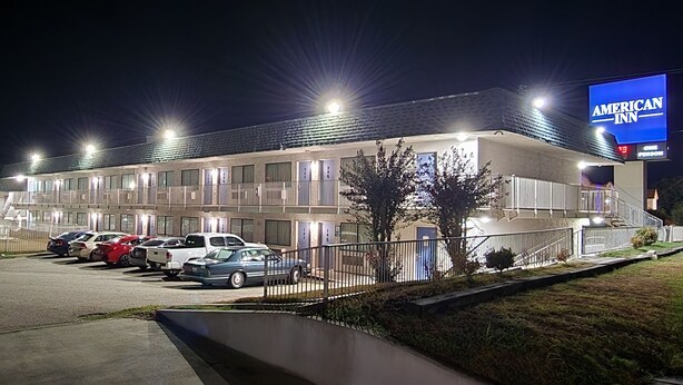 A motel with multiple rooms, a parking lot, and a sign for American Inn. - AMERICAN INN (Temple)