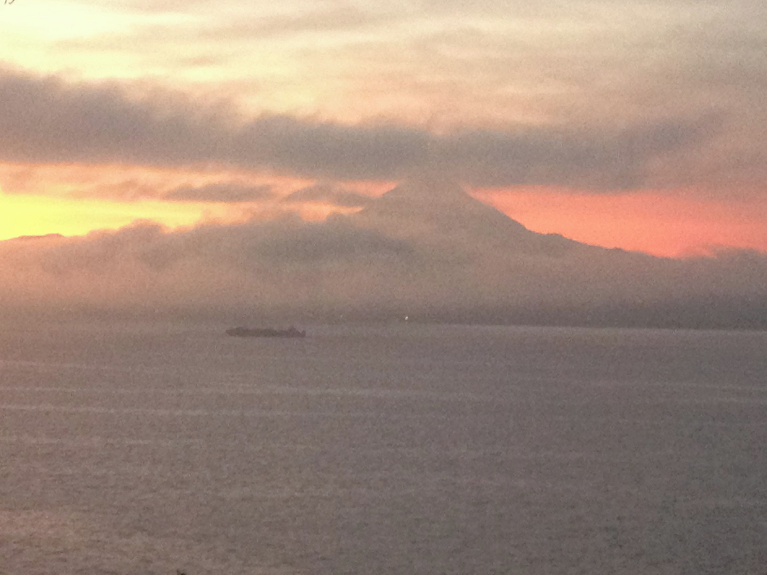 A ship on a calm sea with a mountain in the background.
