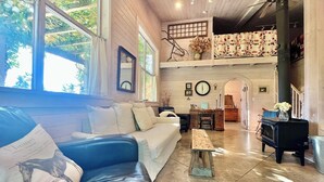 A cozy living room with a sofa, a coffee table, a fireplace, and a staircase leading to an upper level. - 40 Acre Estate, Beach Access, Horses, Sleeps up to 6 on Vashon Island (Vashon)