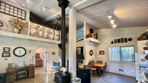 A spacious living area with a high ceiling, a fireplace, a dining table, and a large window. - 40 Acre Estate, Beach Access, Horses, Sleeps up to 6 on Vashon Island (Vashon)