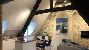 Un espace de vie chaleureux de style loft, comprenant une cuisine, un coin repas et une grande fenêtre.